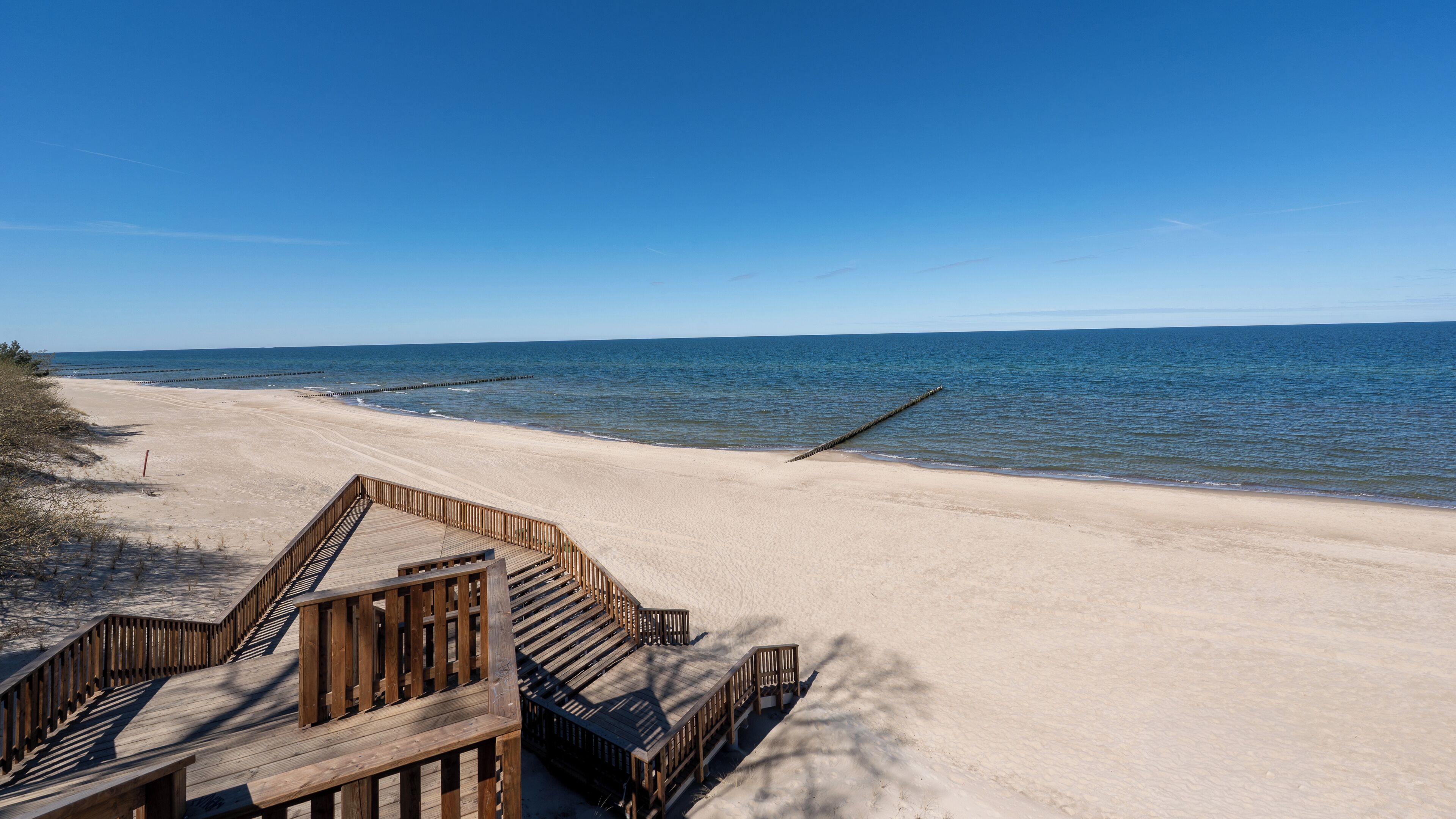 Ein Strand mit Holzstegen und freiem Blick auf den Ozean.