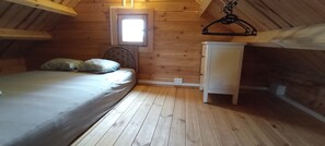 A small attic bedroom with a single bed, a white cabinet, and a window with natural light.