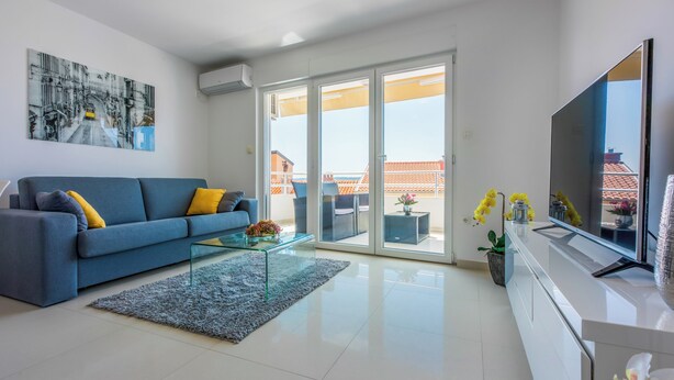 A modern living room with a sofa, glass coffee table, and a flat-screen TV. - Modern apartment with sun terrace and sea view (Crikvenica)