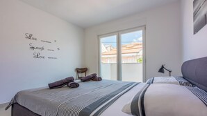 A bedroom with a bed, pillows, a wall with motivational quotes, a window, and a door. - Modern apartment with sun terrace and sea view (Crikvenica)