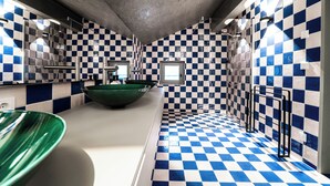 Un baño con paredes y piso de baldosas a cuadros, un lavamanos verde y una ventana.