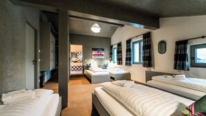 Habitación de hotel con tres camas, kitchenette, piso a cuadros y un cartel de Lioroil.
