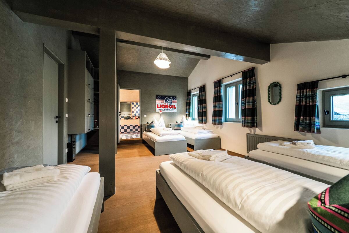 A hotel room with three beds, a kitchenette, a checkered floor, and a sign for Lioroil.