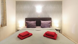 Ein Hotelzimmer mit einem großen Bett, zwei Nachttischlampen und einer Wandleuchte.