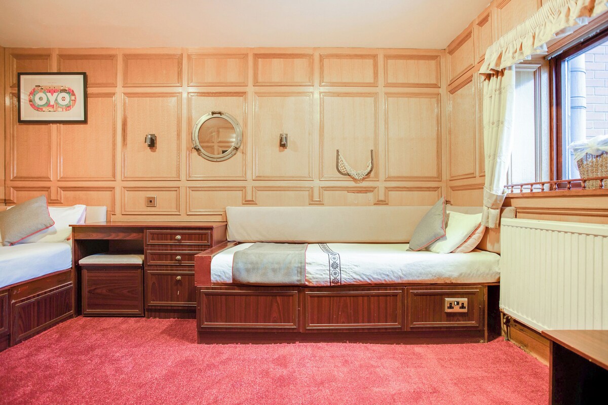 A bedroom with two beds, wooden paneling, a mirror, and a radiator.