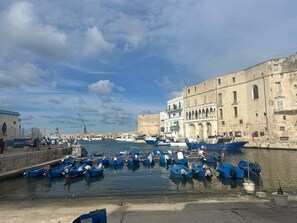 A harbor with boats docked, a stone building with arches, and a clear sky. - Gargano Palace (Monopoli)
