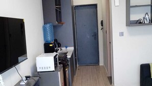 A modern living room with a flat-screen TV, a glass coffee table, a sofa, and a kitchen area with a microwave, kettle, and water dispenser. - Relax in Style: Fully Furnished Studio Apartment. Secure and amazing in Nairobi (Nairobi)