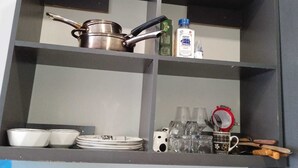 A kitchen shelf with cookware, a bottle of KENSALT, and glassware. - Relax in Style: Fully Furnished Studio Apartment. Secure and amazing in Nairobi (Nairobi)