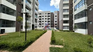 A modern apartment complex with a central pathway, multiple floors, and a playground in the background. - Relax in Style: Fully Furnished Studio Apartment. Secure and amazing in Nairobi (Nairobi)