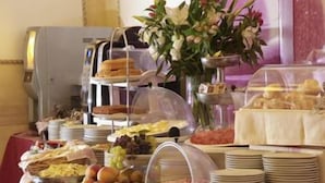 A buffet with various food items, including fruits, meats, and pastries, arranged on a table with a clear glass dome covering some dishes. - Hotel Villa Rosa (Modica)