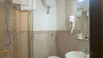 A bathroom with a shower, toilet, sink, and a mirror.
