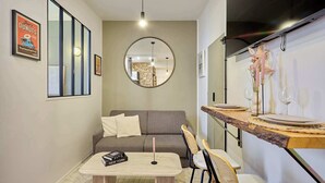 Un ambiente compatto con divano, un piccolo tavolo da pranzo e uno specchio.