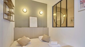 Camera d'albergo con un letto, due cuscini, una testiera, una lampada a parete, un quadro incorniciato e uno specchio.