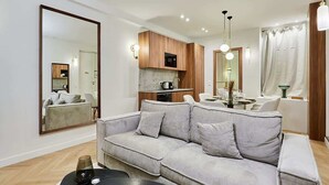Un salon moderne avec un canapé gris, une table basse et un coin repas comprenant une table et des chaises.