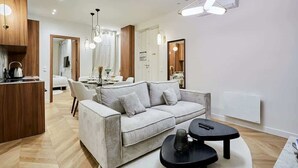 Un salon moderne avec un canapé, une table basse et, au fond, un coin repas.