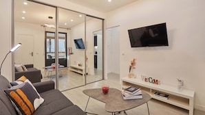 A modern living room with a sofa, a coffee table, a TV, and a bookshelf. - Modern Suite with Patio Boulogne-Billancourt (Boulogne-Billancourt)