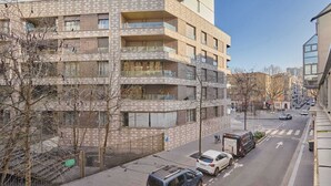 A multi-story building with balconies, a street with parked cars, and a clear sky. - Modern Suite with Patio Boulogne-Billancourt (Boulogne-Billancourt)