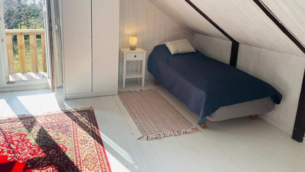 A bedroom with a bed, a nightstand, a lamp, a window, and a view of the outdoors. - 4 Person Holiday Home in Tomelilla (Tomelilla)