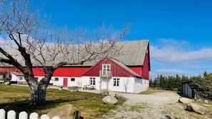 A red and white building with a gravel driveway and a white picket fence. - 4 Person Holiday Home in Tomelilla (Tomelilla)