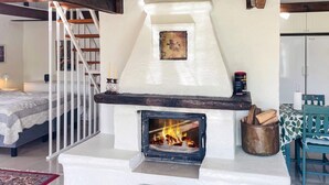 A fireplace with a fire, a staircase, a bed, and a dining area with a table and chairs. - 4 Person Holiday Home in Tomelilla (Tomelilla)