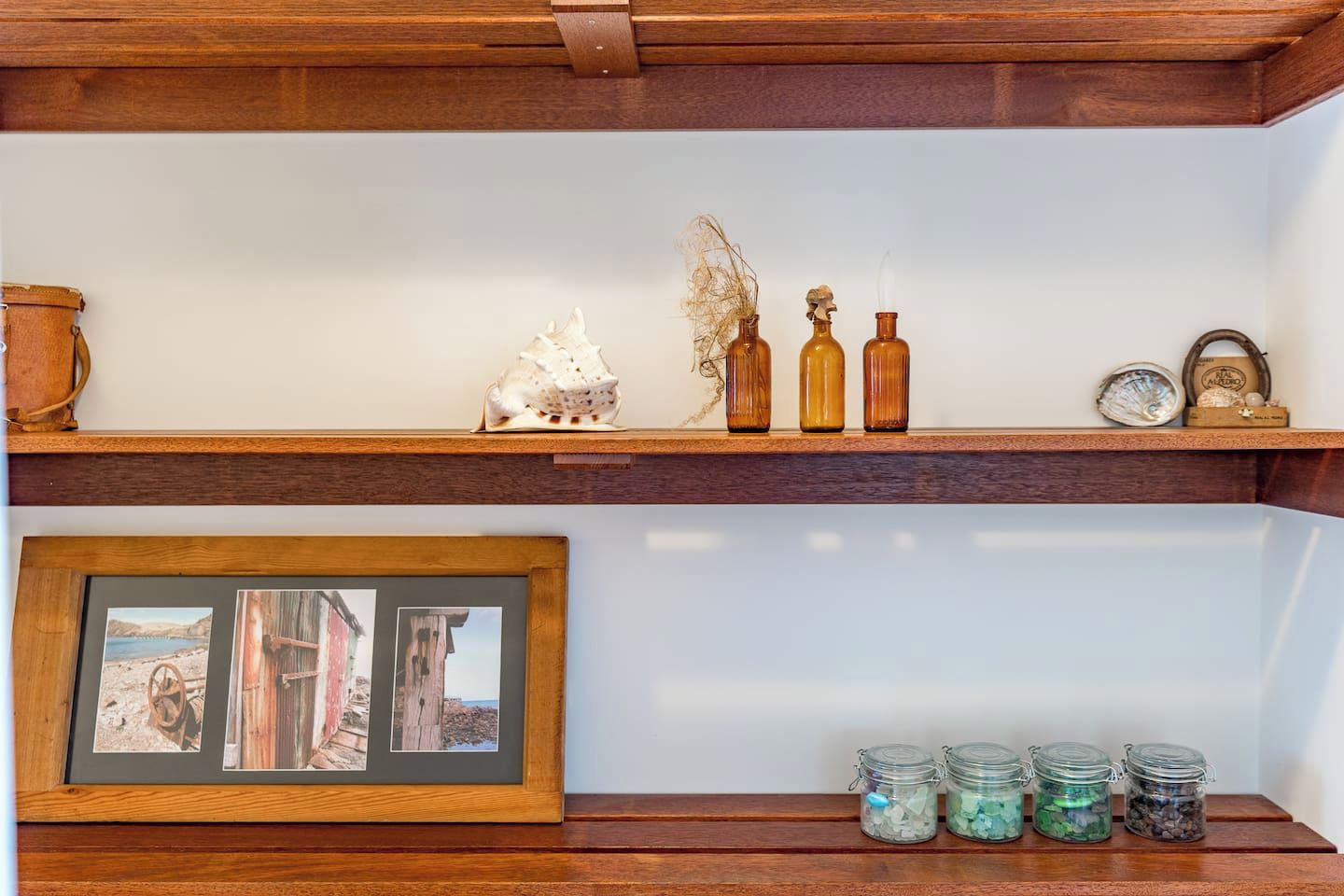 Une étagère en bois ornée d’objets décoratifs, d’une photographie encadrée et de bocaux en verre.