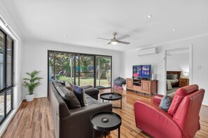 Uma sala de estar moderna com sofá, poltrona vermelha e televisão.