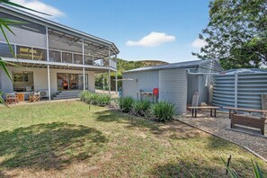 A modern two-story house with a covered patio, a small shed, and a water tank. - Swell Beach House - Families Walk to the Beach (Second Valley)