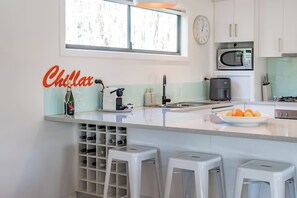 Uma cozinha moderna com uma ilha grande, espaço para armazenamento de vinhos e um relógio na parede.