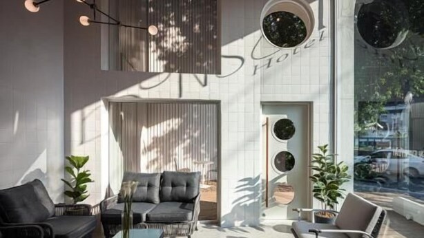 Una moderna hall d'albergo con un'area relax, un tavolino in vetro e un'ampia finestra che offre vista sull'esterno.