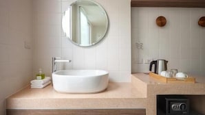 Un bagno moderno con uno specchio rotondo, un lavandino bianco e mobili in legno.