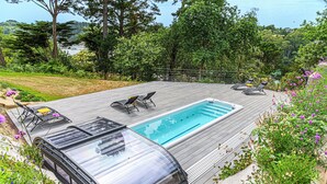 A swimming pool with lounge chairs and a glass-enclosed cabana. - Puffin - Laïta (Guidel)