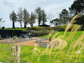 A landscaped garden with a modern building, trees, and a clear sky. - Puffin - Laïta (Guidel)