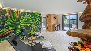 A modern room with a mural of a forest, a wooden cabinet, a stone fireplace, and a large window. - Puffin - Laïta (Guidel)