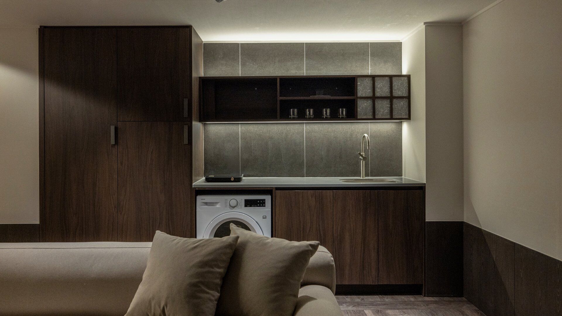 A compact kitchen with a washing machine, built-in cabinets, and a countertop.