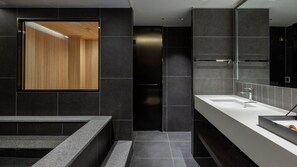 Une salle de bain moderne avec un grand miroir, un mur recouvert de panneaux en bois et un lavabo blanc.
