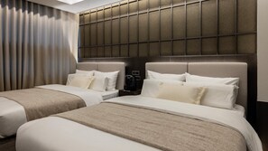 Une chambre d’hôtel avec deux lits, une tête de lit ornée d’un panneau texturé, une machine à café sur la table de chevet et une fenêtre avec des rideaux.