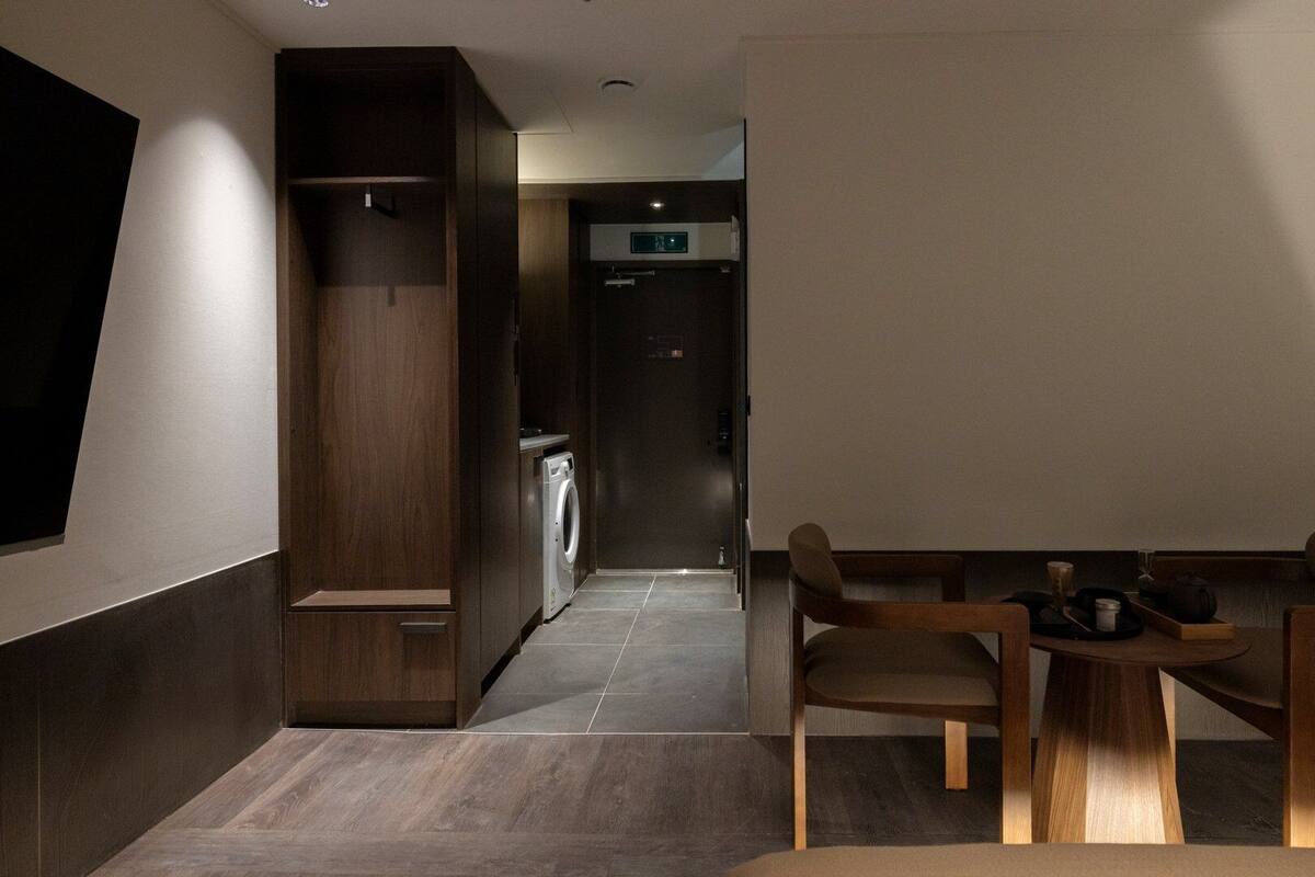 A hotel room with a dining area, a washing machine, and a kitchenette.