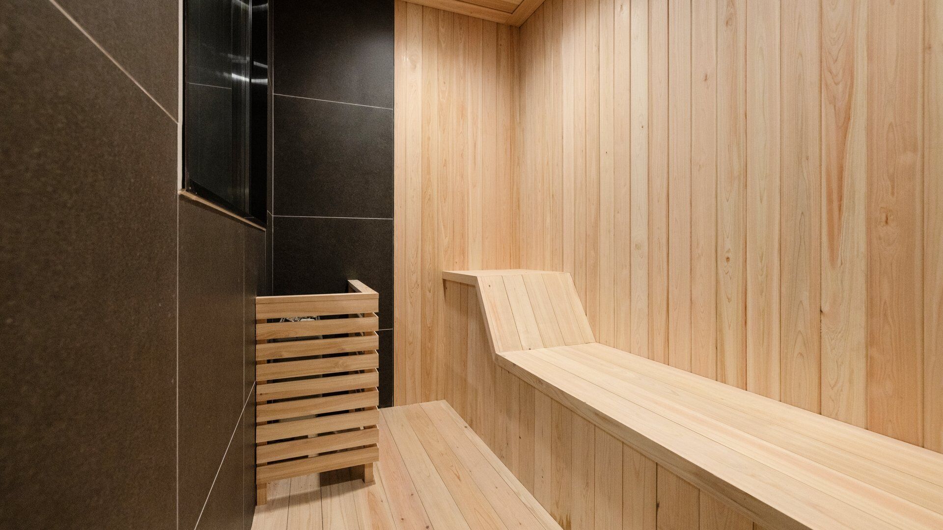 Een sauna met houten banken en een betegelde muur.