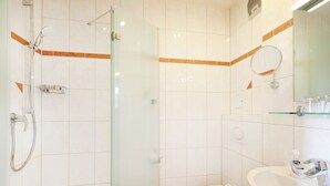 Ein Badezimmer mit einer Duschkabine, einer Toilette und einem Waschbecken mit Toilettenartikeln.
