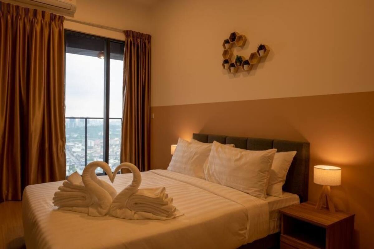 Ein Hotelzimmer mit Bett, Nachttisch, Lampe, einem Fenster mit Vorhängen und einer Wanddekoration.