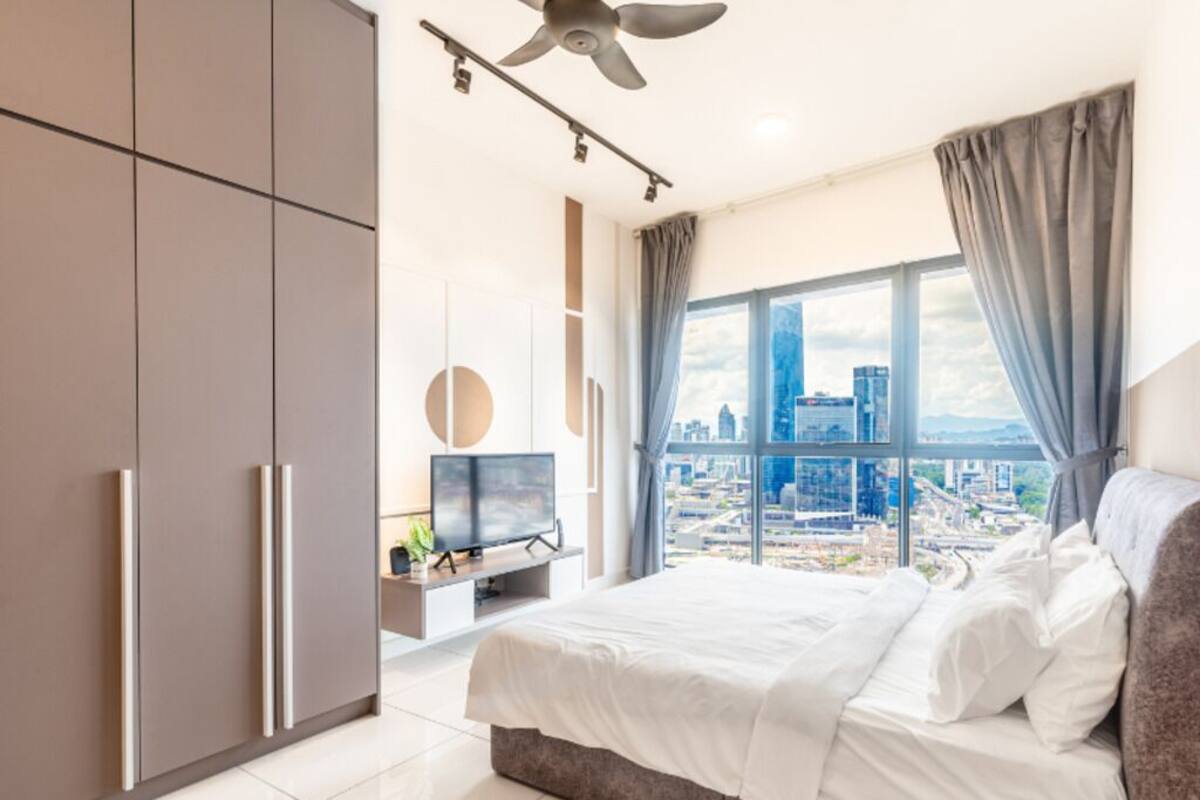 Ein modernes Schlafzimmer mit einem großen Bett, einem Fernseher und Blick auf die Stadt.