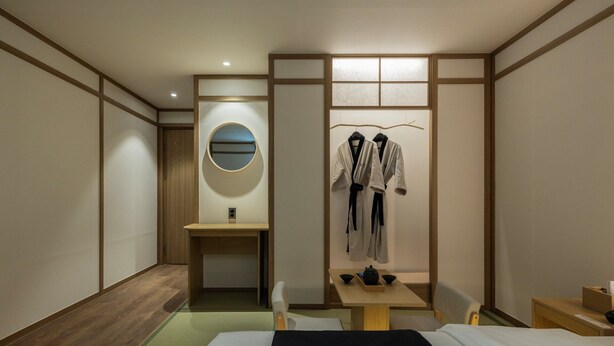 A hotel room with a bed, a desk with a mirror, a wardrobe, and a small table with bowls. - Anook Ryokan Hotel Daejeon Daeheung (Daejeon)
