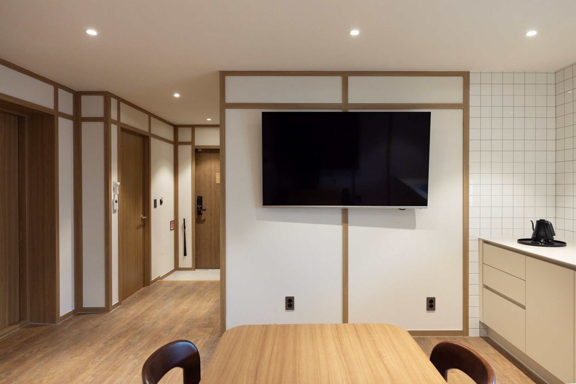 Una cocina moderna con una televisión de pantalla plana en la pared, armarios de madera y una cafetera sobre la encimera.