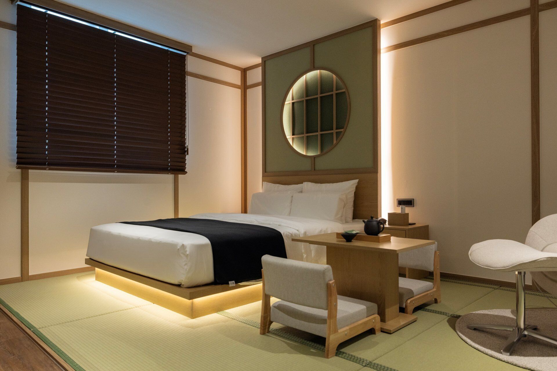 Ein Hotelzimmer mit Bett, Nachttisch, Stuhl und einem runden Spiegel an der Wand.