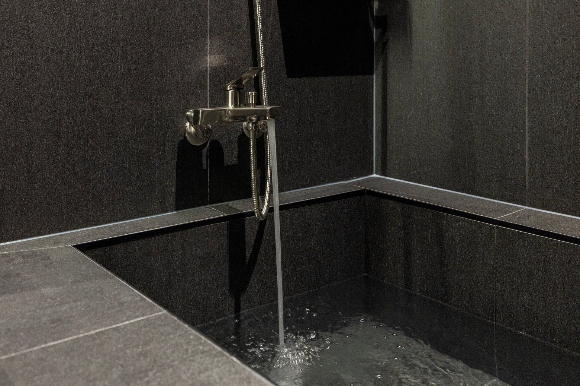 Ducha moderna con cabezal de ducha de mano, una perilla de control y un espejo rectangular.