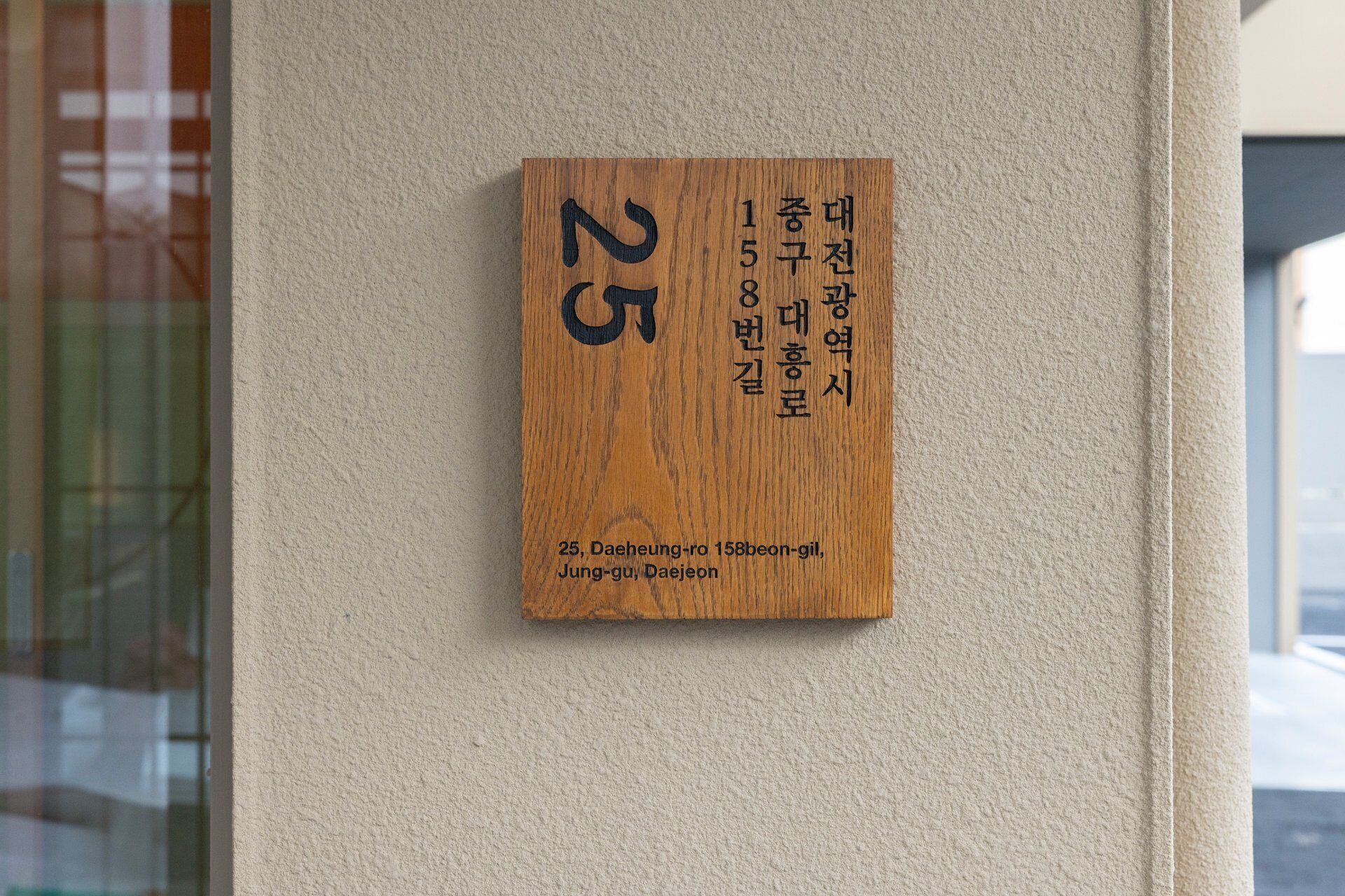 A wooden plaque with a number and Korean text, mounted on a wall.