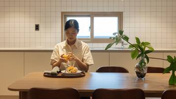 A person seated at a wooden dining table with a plate of food and a glass of orange juice.