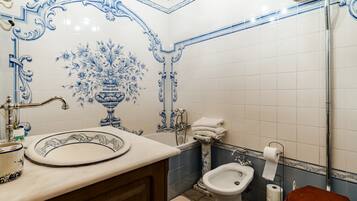 Baño con lavabo, bidé, inodoro y un diseño de azulejos decorativos.