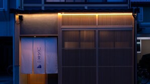Un bâtiment à deux étages avec une grande porte de garage, un vélo garé à l’extérieur et une piste cyclable le long de la rue.