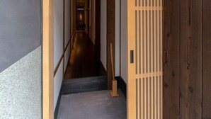 Un couloir avec un cadre de porte en bois, une porte coulissante et un luminaire fixé au mur.
